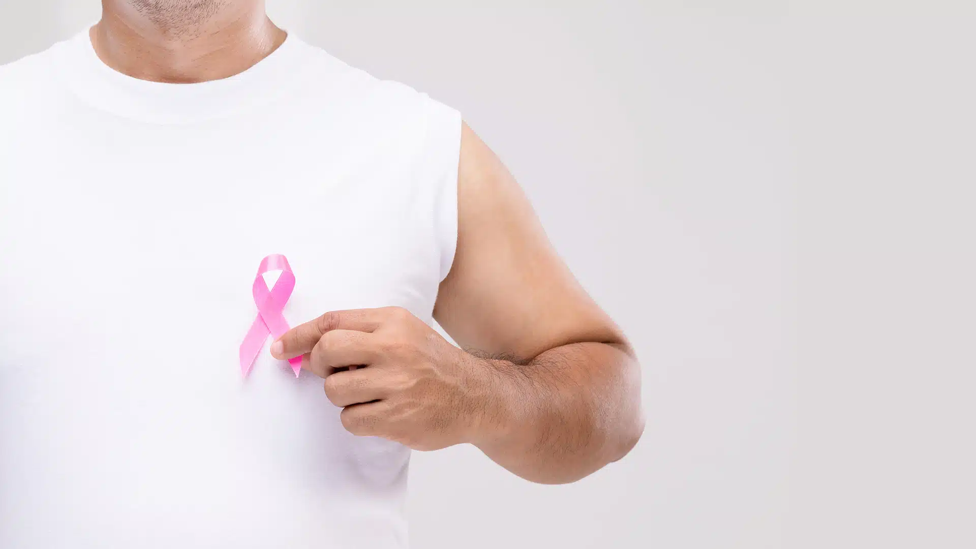 Men-and-Breast-Cancer-Raising-Awareness-and-Dispelling-Myths Man holding a pink ribbon close to his heart.